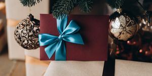 voucher hadiah dalam amplop merah anggur dengan busur biru di bawah pohon natal hadiah natal